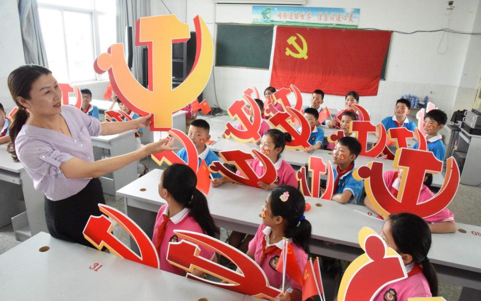 A teacher and her students pose with Communist Party emblems during a class about the history of the Communist Party at a school in Lianyungang, in China's eastern Jiangsu province  - AFP