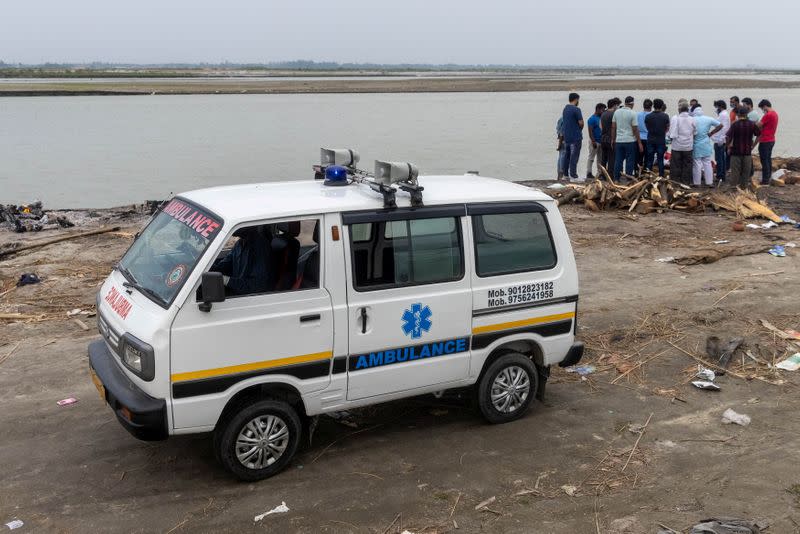 Relatives gather around the body of a man who died from the coronavirus disease (COVID-19), before cremating him on the banks of the river Ganges at Garhmukteshwar