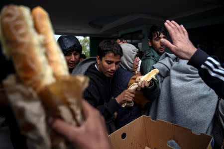 Refugees and migrants receive free food as they take a break at a petrol station before abandoning their trek to the Hungarian border, in the town of Indjija, Serbia October 5, 2016. REUTERS/Marko Djurica