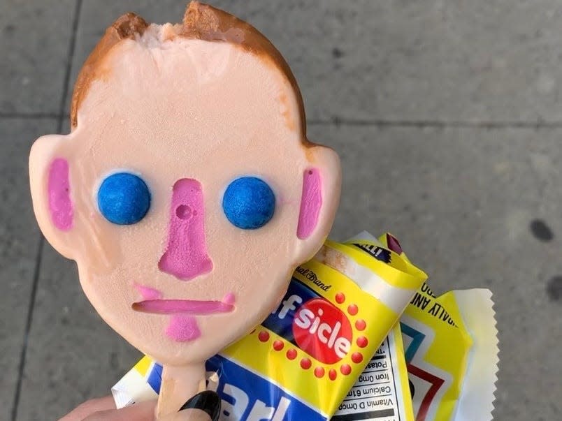 A popsicle shaped like Mark Zuckerberg has a bite taken out of it.