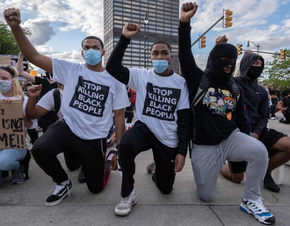 Protesters raise their fists as they kneel in front of a police station in Detroit, Michigan, on 30 May.