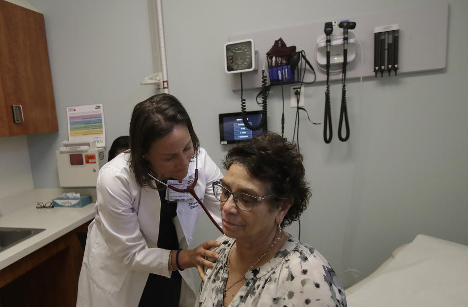 In this April 9, 2019 photo, Dr. Megan Mahoney, left, examines patient Consuelo Castaneda at the Stanford Family Medicine office in Stanford, Calif. Rapidly evolving technology and a surge in options like walk-in clinics or urgent care centers are creating many new front doors to health care instead of one main opening through the doctor's office. (AP Photo/Jeff Chiu)