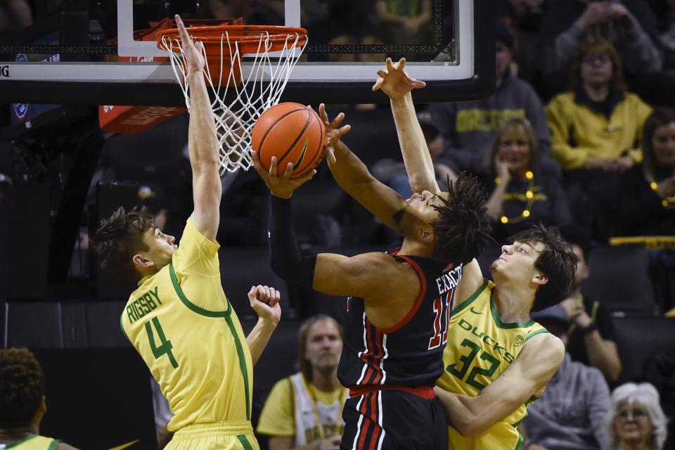 Utah guard Wilguens Exacte Jr. (11) is defended by Oregon guard Brennan Rigsby (4) and center Nate Bittle (32) during the first half of an NCAA college basketball game Saturday, Jan. 28, 2023, in Eugene, Ore. (AP Photo/Andy Nelson)