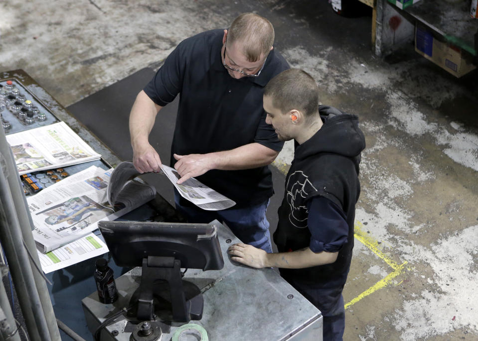 In this Thursday, April 11, 2019 photo pressmen Kit Stover, of Richmond, Mass., left, and Lukus Ladeinde, of Pittsfield, Mass., right, check for correct registration of print from a sample of a newspaper fresh off the press at The Berkshire Eagle newspaper, in Pittsfield, Mass. The paper now features a new 12-page lifestyle section for Sunday editions, a reconstituted editorial board, a new monthly magazine, and the newspaper print edition is wider. That level of expansion is stunning in an era where U.S. newspaper newsroom employment has shrunk by nearly half over the past 15 years. (AP Photo/Steven Senne)