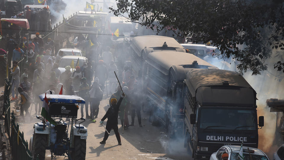 NEW DELHI, INDIA - JANUARY 26: Farmers brave tear gas shells fired by Delhi Police during the tractor march from Tikri border, at Nagloi Crossing, on January 26, 2021 in New Delhi, India. Major scenes of chaos and mayhem at Delhi borders as groups of farmers allegedly broke barricades and police check posts and entered the national capital before permitted timings. Police used tear gas at Delhi's Mukarba Chowk to bring the groups under control. Clashes were also reported at ITO, Akshardham. Several rounds of talks between the government and protesting farmers have failed to resolve the impasse over the three farm laws. The kisan bodies, which have been protesting in the national capital for almost two months, demanding the repeal of three contentious farm laws have remained firm on their decision to hold a tractor rally on the occasion of Republic Day.(Photo by Raj K Raj/Hindustan Times via Getty Images)