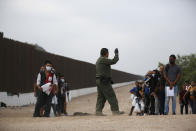 A Border Patrol agent instructs migrants who had crossed the Rio Grande river into the U.S. in Eagle Pass, Texas, Friday, May 20, 2022. The Eagle Pass area has become increasingly a popular crossing corridor for migrants, especially those from outside Mexico and Central America, under Title 42 authority, which expels migrants without a chance to seek asylum on grounds of preventing the spread of COVID-19. A judge was expected to rule on a bid by Louisiana and 23 other states to keep Title 42 in effect before the Biden administration was to end it Monday. (AP Photo/Dario Lopez-Mills)
