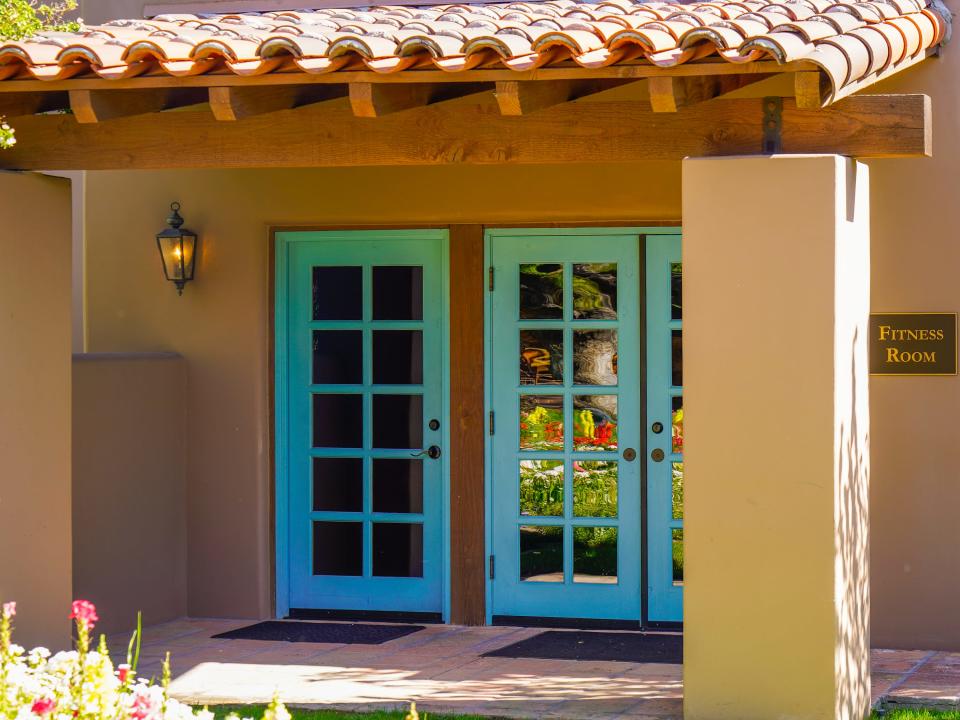 A tan adobe building with blue windowed doors