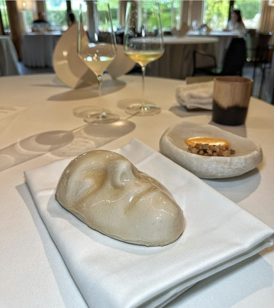 Elegant dining table set with artistic bread, wine glasses, and a dish with nuts, in a fine restaurant setting