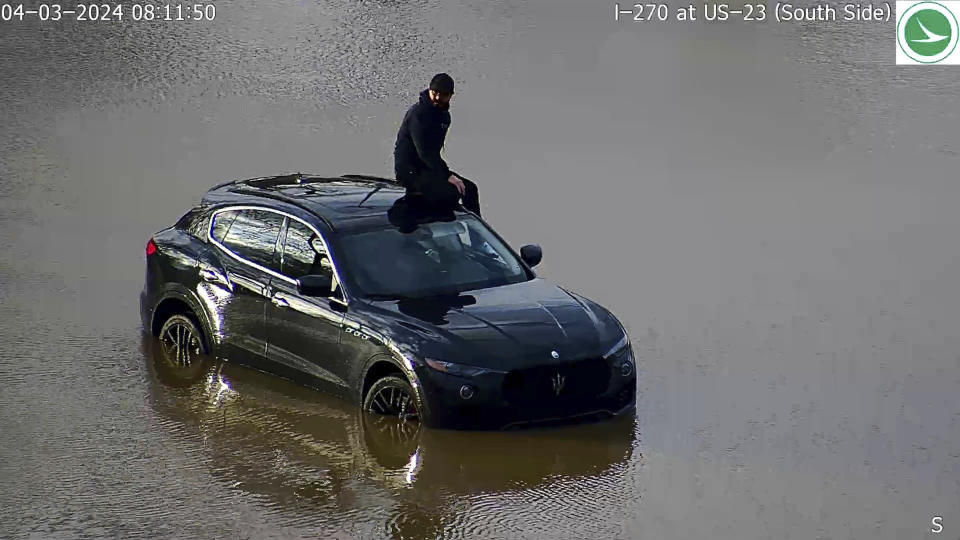 In this image released by the Ohio Department of Transportation, a person is seen stranded on his vehicle in flood waters at I-270 and US 23 in Columbus' South Side, Ohio, Tuesday, April 3, 2024. Authorities said the driver drove around barricades on Wednesday morning around 8 a.m and stranded in high water. The barricades were placed since Tuesday afternoon as water from the Scioto River continued to rise due to heavy rainall in the region. (Ohio Department of Transportation via AP)