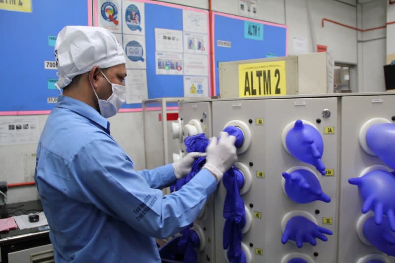 A worker inspects newly made gloves at Top Glove factory in Klang