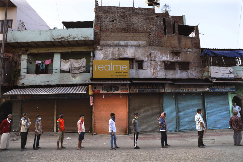 Homeless people stand in a queue to receive food distributed by the volunteers during the nation wide 21 day lockdown amid concern over the spread of coronavirus, in New Delhi, India, Monday, April 6, 2020. The new coronavirus causes mild or moderate symptoms for most people, but for some, especially older adults and people with existing health problems, it can cause more severe illness or death. (AP Photo/Manish Swarup)