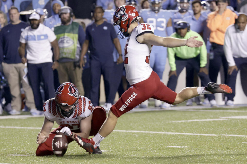 North Carolina State's Christopher Dunn (32) hits a field goal against North Carolina from the hold of Shane McDonough (97) during the second overtime in an NCAA college football game Friday, Nov. 25, 2022, in Chapel Hill, N.C. (AP Photo/Chris Seward)