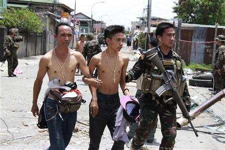 Government soldiers escort residents who were taken hostage and used as human shields by Muslim rebels of Moro National Liberation Front (MNLF) during fighting with government soldiers, in Zamboanga city in southern Philippines September 17, 2013. REUTERS/Stringer