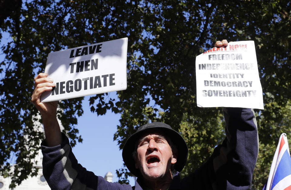 A demonstrator holds placards outside the Supreme Court in London, Wednesday, Sept. 18, 2019. The Supreme Court is set to decide whether Prime Minister Boris Johnson broke the law when he suspended Parliament on Sept. 9, sending lawmakers home until Oct. 14 — just over two weeks before the U.K. is due to leave the European Union. (AP Photo/Kirsty Wigglesworth)