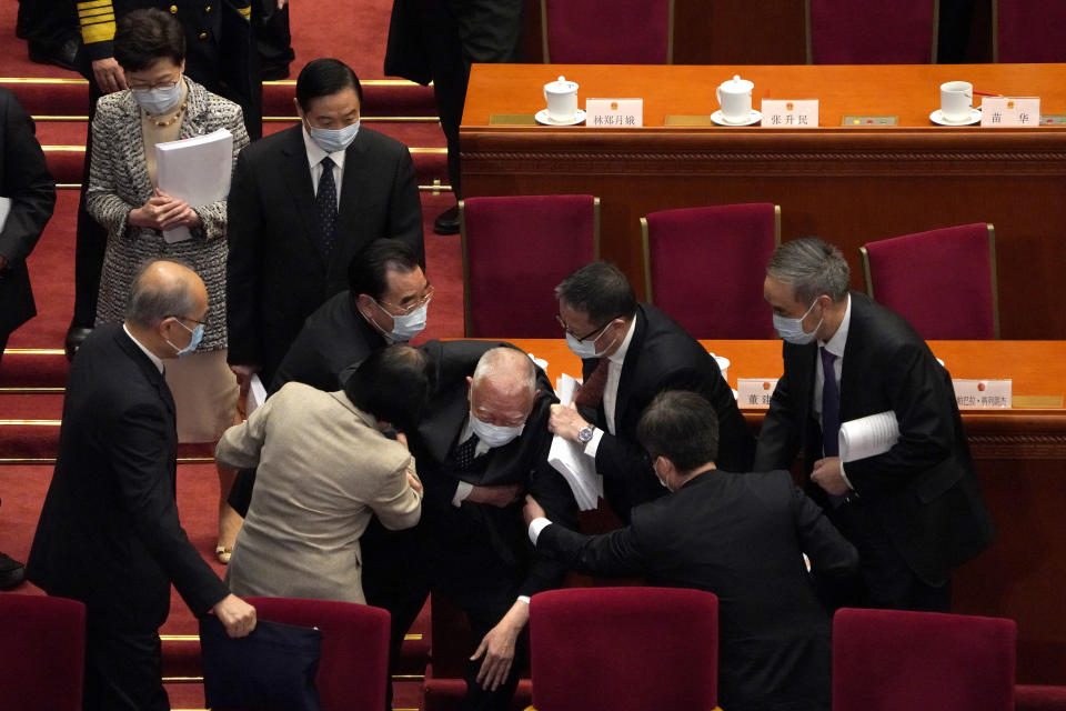 Hong Kong Chief Executive Carrie Lam, top left, watches as attendees help former Hong Kong Chief Executive Tung Chee-hwa after he fell following the opening session of China's National People's Congress (NPC) at the Great Hall of the People in Beijing, Friday, March 5, 2021. (AP Photo/Andy Wong)