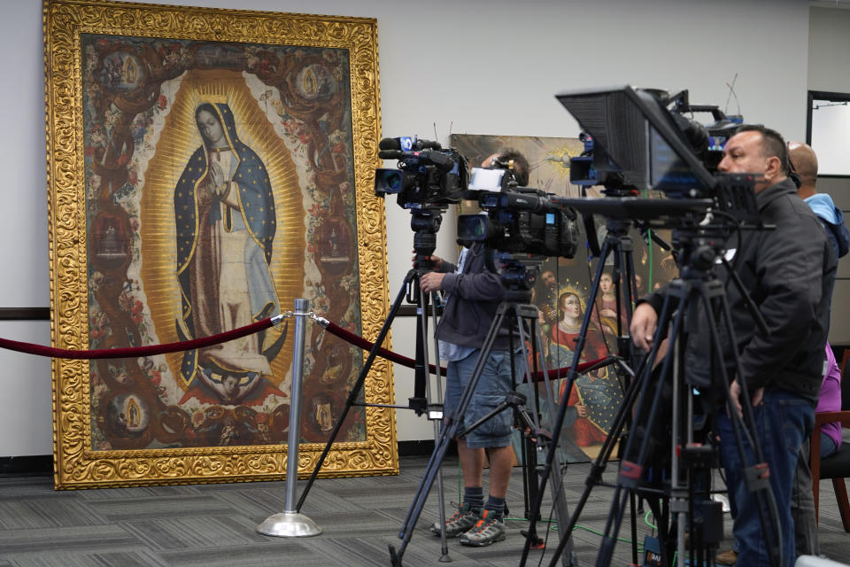 Members of the media attend a repatriation ceremony following investigations by the FBI's Art Crime Team at the FBI headquarters in Los Angeles Friday, April 22, 2022. Left, the "Virgin of Guadalupe" painting was stolen from the Santiago Apostle Church, also known as "Saint James Apostle," in Ollantaytambo, Peru, with six other paintings. The FBI returned sixteen cultural items to representatives of the Peruvian government, from its pre-Columbian era through its Spanish Colonial Period and into the 20th Century. (AP Photo/Damian Dovarganes)