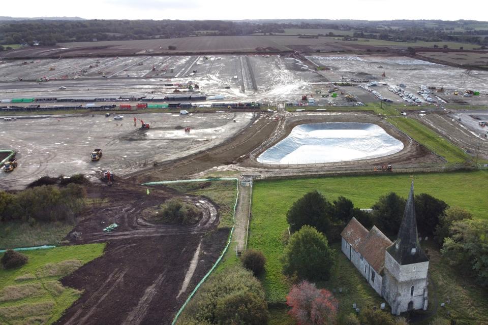 An aerial picture shows St Mary's Church in the foreground as construction continues at a site of a lorry park being built between the villages of Sevington and Mersham, near the M20 motorway near Ashford in Kent, south east England on October 6, 2020, which will have the capacity to hold nearly 10,000 vehicles in the event of a no-deal Brexit. - Queues of up to 7,000 heavy-goods vehicles could develop in southeast England from January if Britain leaves the European Union without a Brexit trading deal, the government forecast last month. In case of a no-deal Brexit, Britain's government is developing giant lorry parks in Kent to prevent gridlock on the road system leading in and out of London. (Photo by BEN STANSALL / AFP) (Photo by BEN STANSALL/AFP via Getty Images)