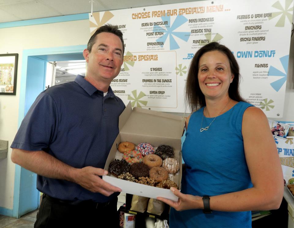 Top That! Donuts husband-and-wife owners Danielle and Chris Wolowitz are shown with a dozen of their specialty topped donuts at the Point Pleasant Beach shop Thursday, May 26, 2022.  