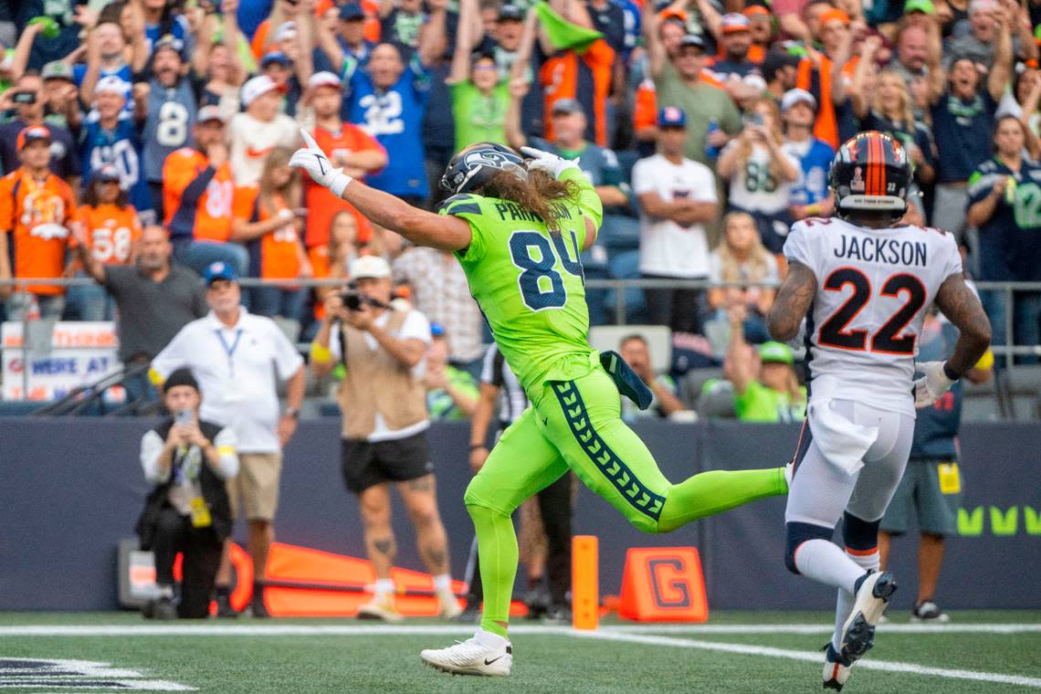 After catching a pass from quarterback Geno Smith (7), Seattle Seahawks tight end Colby Parkinson (84) runs into the endzone for a touchdown as Denver Broncos safety Kareem Jackson (22) looks on during the second quarter of an NFL game on Monday, Sept. 12, 2022, at Lumen Field in Seattle.