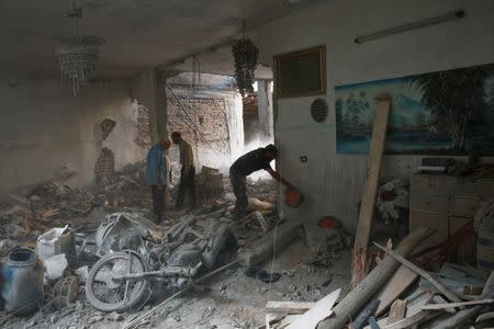 People inspect a damaged site in Arbin, a town in the Damascus countryside, Syria July 25, 2017. REUTERS/Bassam Khabieh