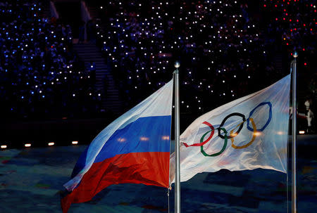 FILE PHOTO: The Russian national flag flutters next to the Olympics flag during the closing ceremony for the 2014 Sochi Winter Olympics, February 23, 2014. REUTERS/Issei Kato/File Photo