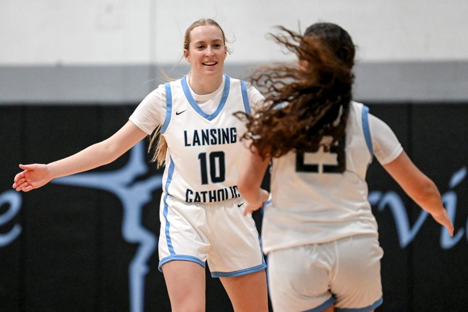 Lansing Catholic's Anna Richards, left, celebrates with Gabby Halliwill, right, after Hallwill's 3-pointer against Williamston during the first quarter on Tuesday, Dec. 12, 2023, at Lansing Catholic High School.