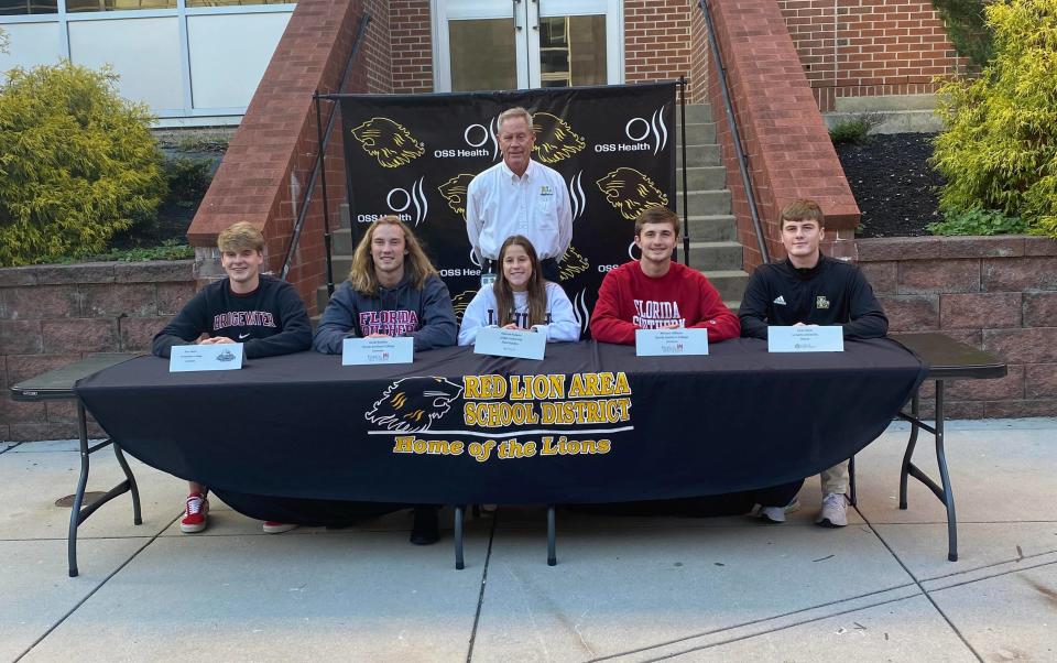 Five Red Lion athletes signed to continue their athletic careers in college Wednesday, Nov. 10. From left: Evan Mader, Jake Bradley, Hannah Downs, Mikey Wilburn, Evan Watt pose with athletic director Arnie Fritzius Wednesday.