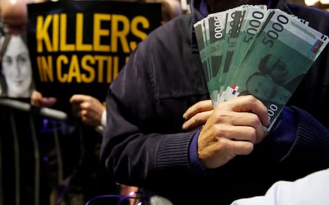 A protester holds fake banknotes depicting Maltese Prime Minister Joseph Muscat, during a demonstration demanding justice over the murder of journalist Daphne Caruana Galizia, outside the Court of Justice, in Valletta - Credit: Reuters