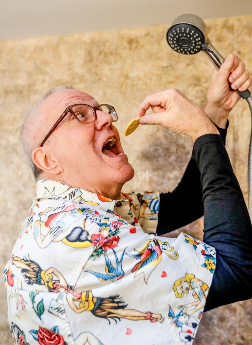 IU grad Dave Hoffman recreates a newspaper photo of himself eating a cracker in the shower on Wednesday, Jan. 5, 2022, at his Indianapolis home. Hoffman set a Guinness world record for longest shower ever taken, 174 hours, on Jan. 27, 1972, in his dorm at IU.