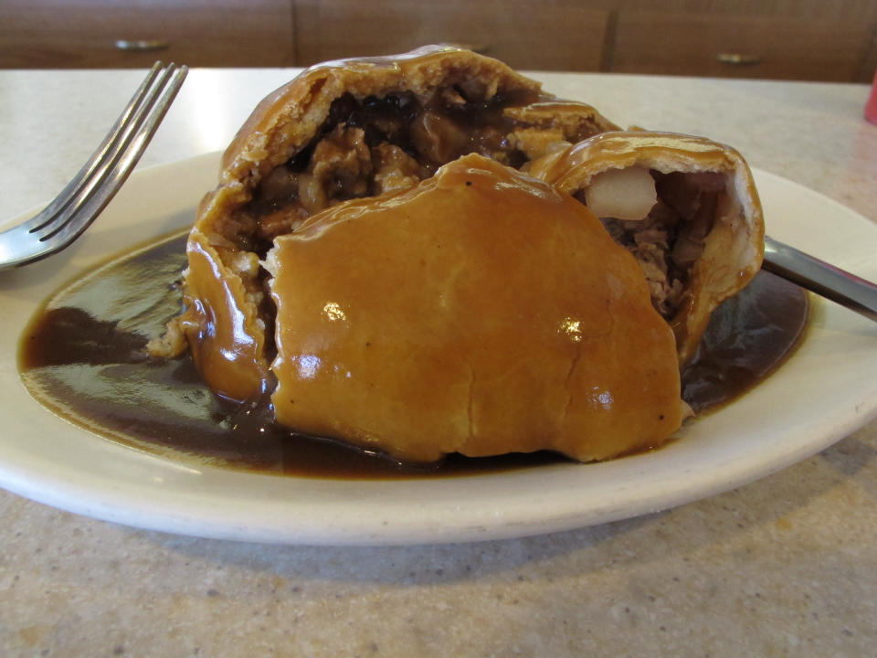 This July 20, 2013 photo shows a meat-filled pasty with gravy from Joe's Pasty Shop in Butte, Mont. The shop is one of a handful that serve the meat-and-potato pie that immigrant miners brought a century ago and has remained a part of Butte's culinary culture. (AP Photo/Matt Volz)