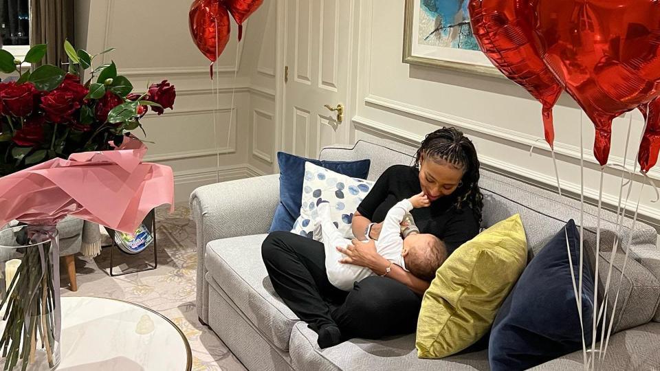 Alexandra Burke holding baby on sofa