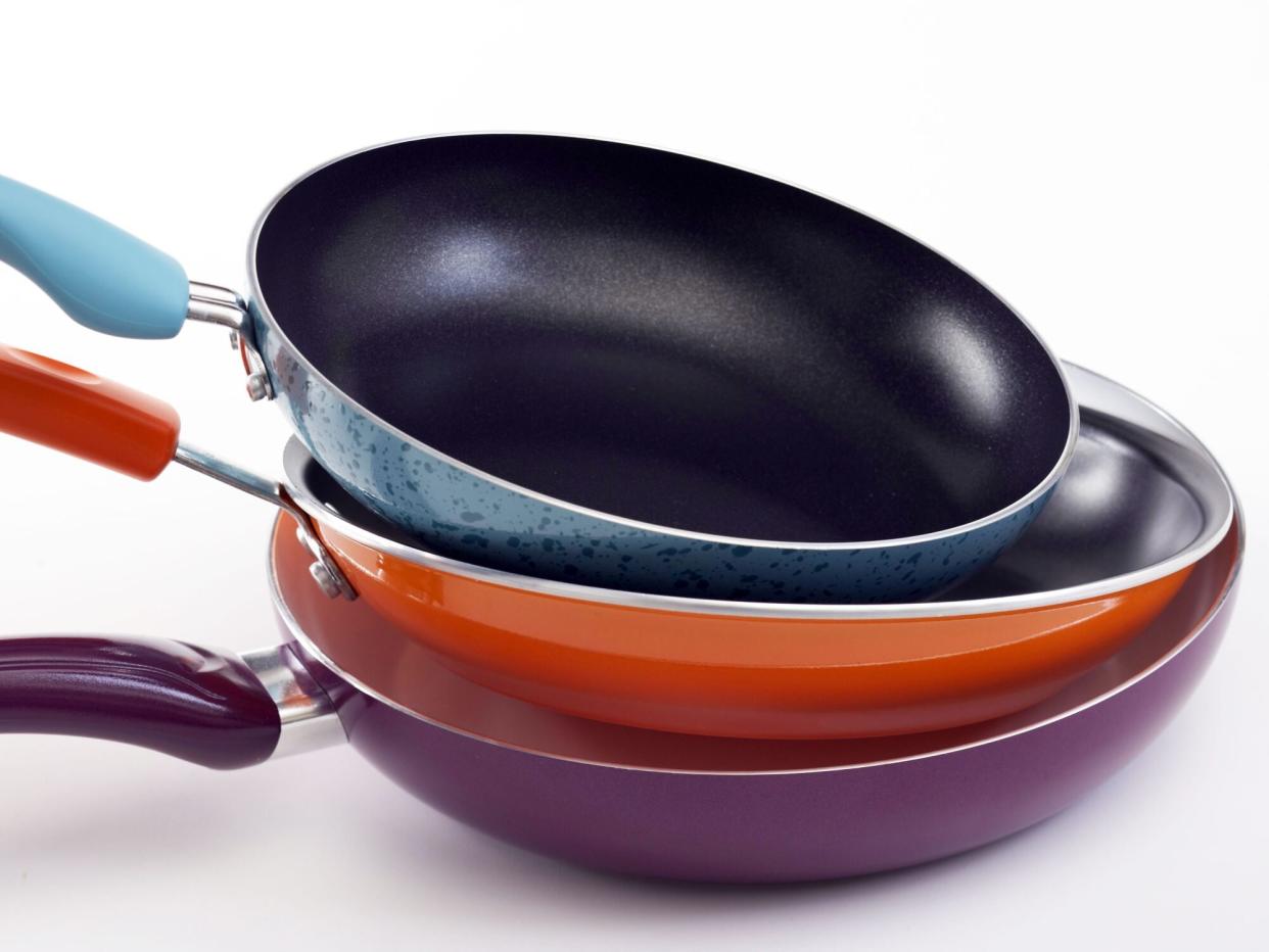 three nonstick pans stacked in front of a white background