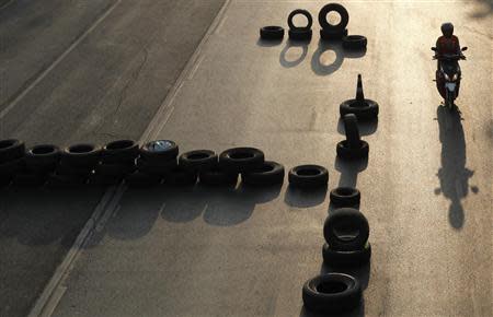 A motorcyclist drives past barricades erected by anti-government protesters in Bangkok's financial district January 23, 2014. REUTERS/Paul Barker