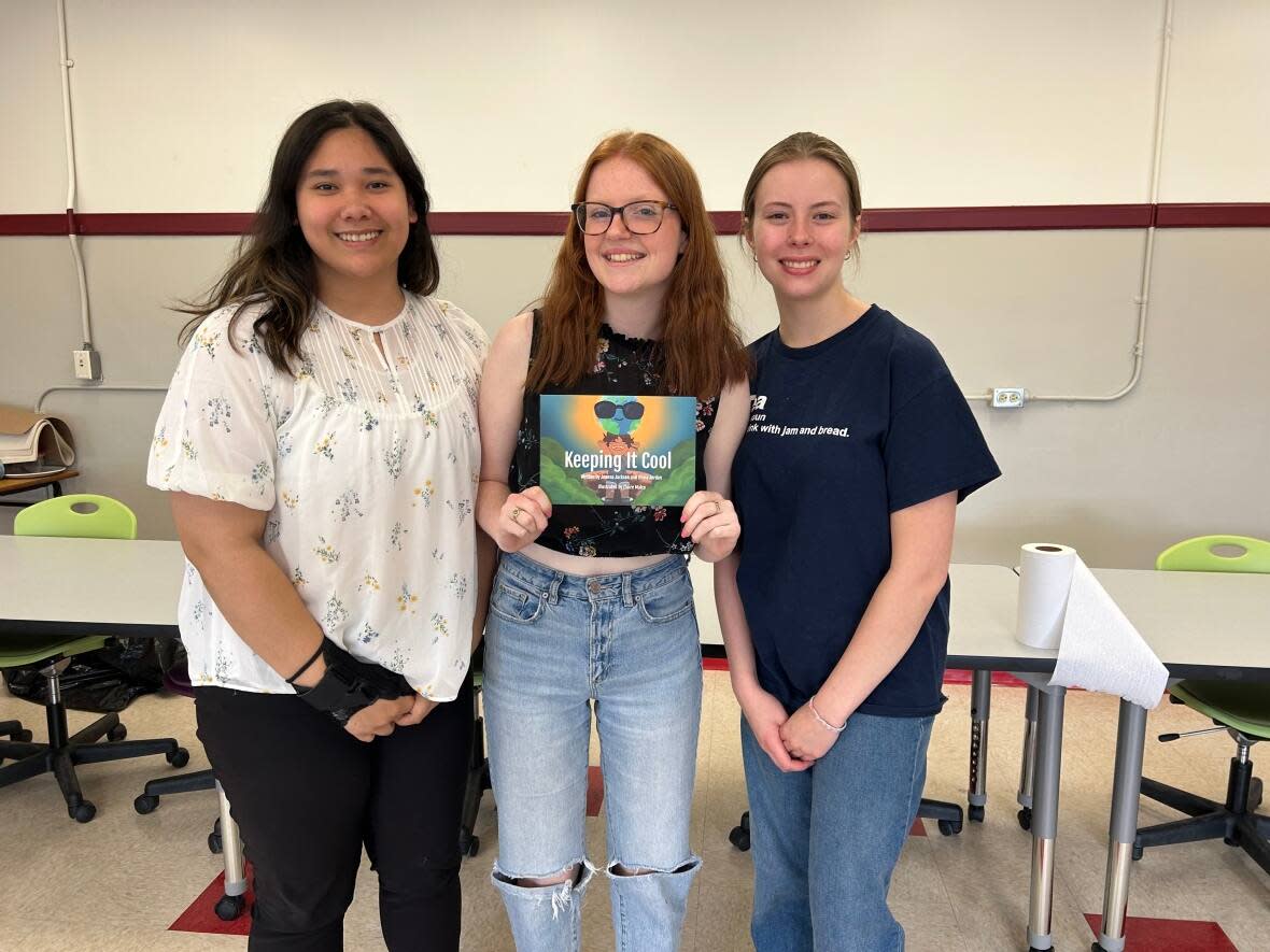 Illustrator Claire Malco and authors Joanna Jackson and Olivia Jordan hold up a copy of their book, Keeping it Cool. (Megan MacAlpine/CBC - image credit)