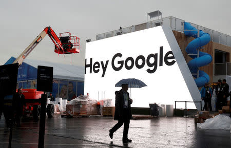 FILE PHOTO: A man walks through light rain in front of the Hey Google booth under construction at the Las Vegas Convention Center in preparation for the 2018 CES in Las Vegas, Nevada, U.S. January 8, 2018. REUTERS/Steve Marcus/File Photo