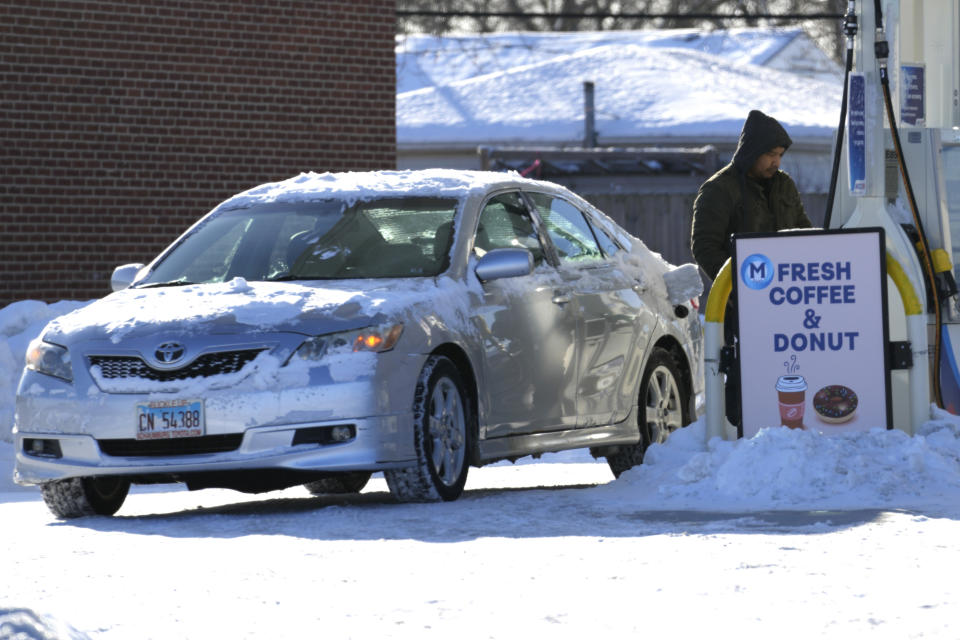 A man checks on gasoline prices at a gas station in Arlington Heights, Ill., Sunday, Jan. 14, 2024. Wind chill warning is in effect as dangerous cold conditions continue in the Chicago area. (AP Photo/Nam Y. Huh)