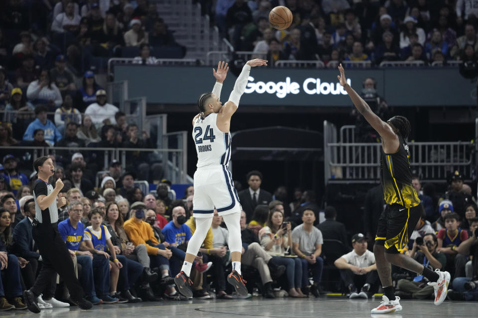 Memphis Grizzlies forward Dillon Brooks, left, shoots a 3-point basket over Golden State Warriors forward Kevon Looney during the first half of an NBA basketball game in San Francisco, Sunday, Dec. 25, 2022. (AP Photo/Godofredo A. Vásquez)