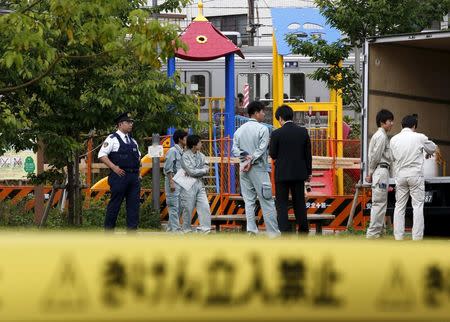 Workers of Tokyo's Toshima ward office and police officers are seen in front of the playground equipment where high levels of radiation were detected at a park in Toshima ward, Tokyo April 24, 2015. REUTERS/Toru Hanai