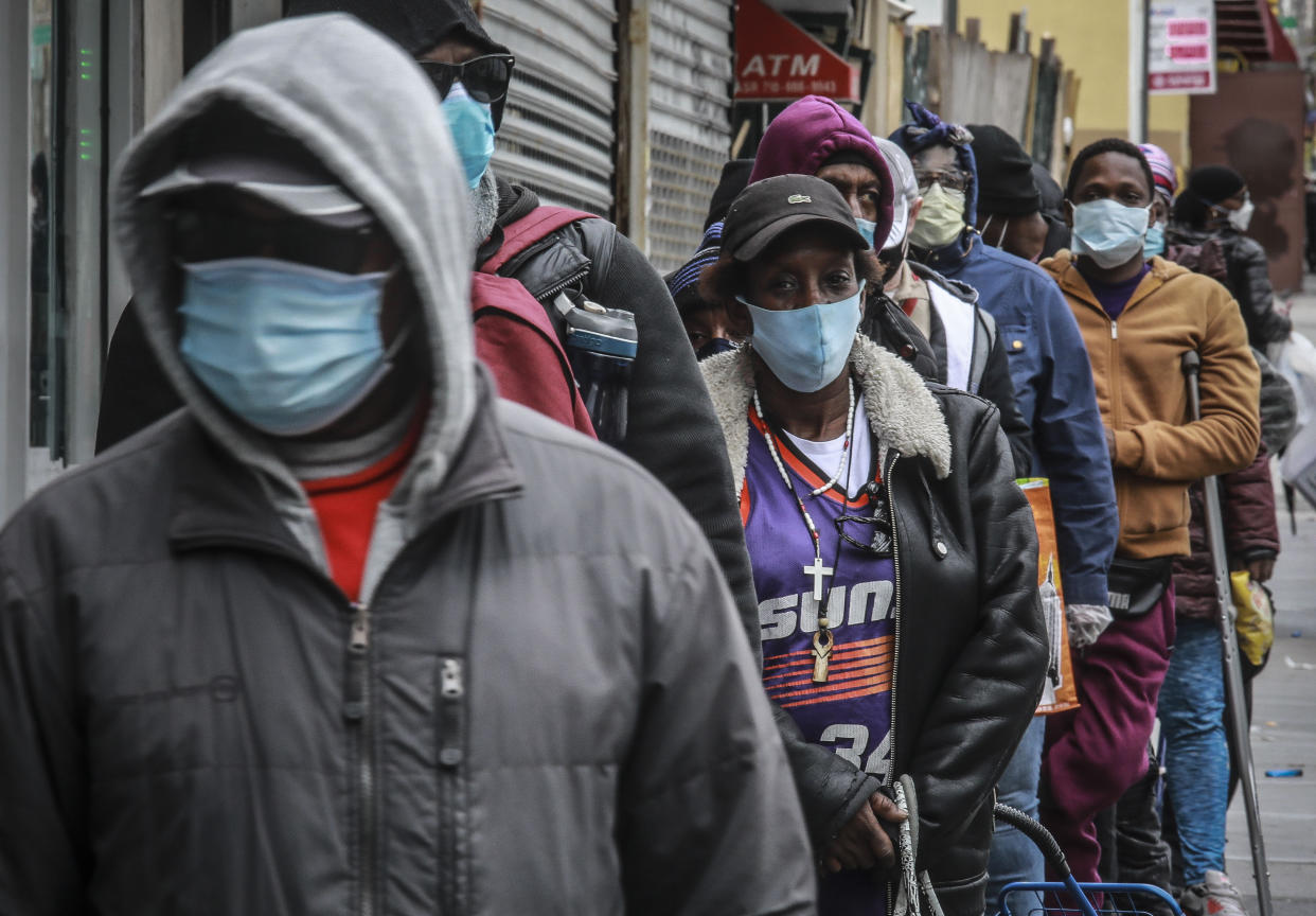 People wait for a distribution of masks and food from the Rev. Al Sharpton in the Harlem neighborhood of New York, after a new state mandate was issued requiring residents to wear face coverings in public due to COVID-19, Saturday, April 18, 2020. "Inner-city residents must follow this mandate to ensure public health and safety," said Sharpton. The latest Associated Press analysis of available data shows that nearly one-third of those who have died from the coronavirus are African American, even though blacks are only about 14% of the population. (AP Photo/Bebeto Matthews)