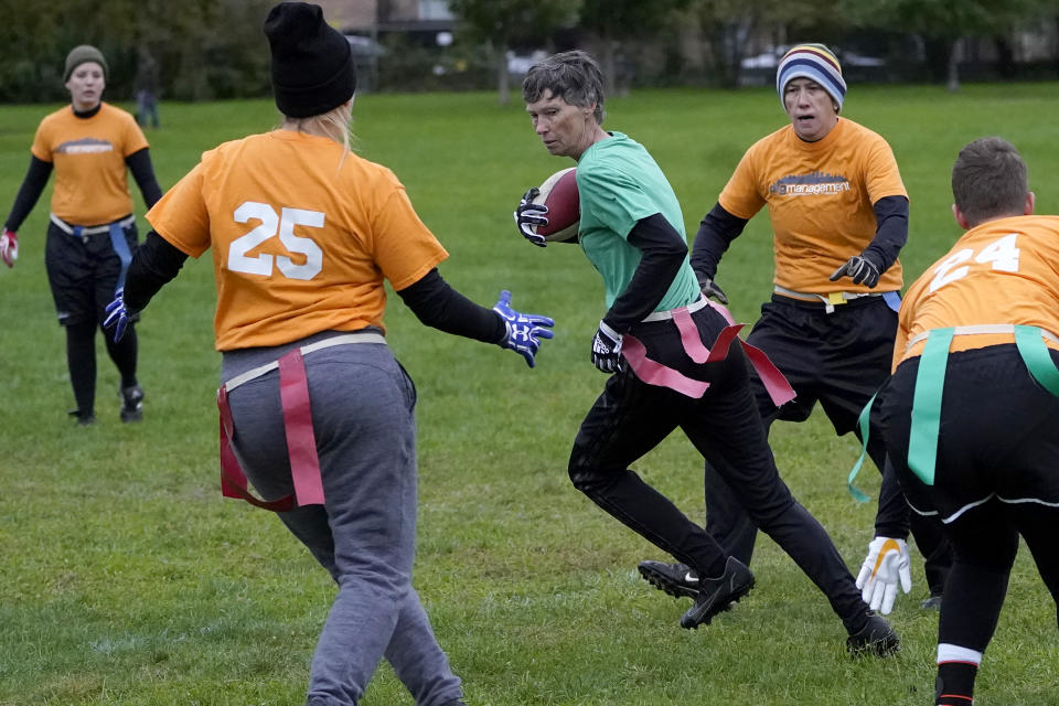 Cyndi Marler, center, advances the ball after a pass reception while playing in a women's flag football league Sunday, Oct. 24, 2021, in Chicago. (AP Photo/Charles Rex Arbogast)