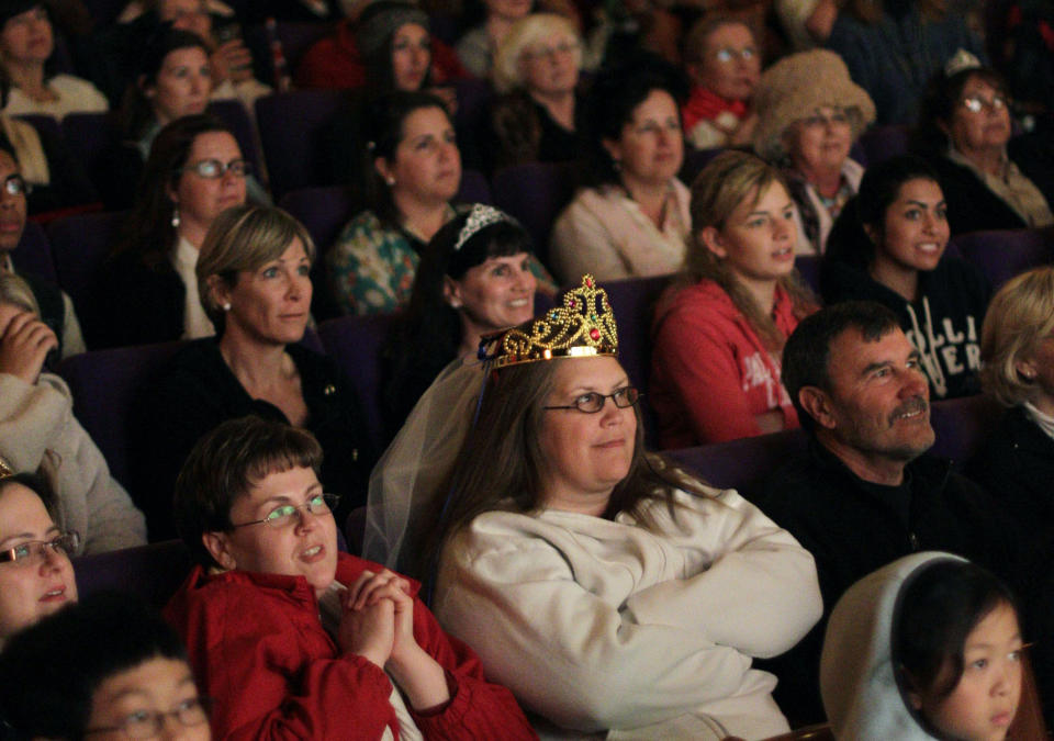 FILE - Sandy Weimer, wearing a tiara, and Cathy Dettman, left, attend a royal wedding "hat and pajamas" party at the Cameo Cinema, April 29, 2011, in St. Helena, Calif., where more than 150 people filled the theater in the middle of the night to watch a live broadcast of the royal wedding of Britain's Prince William and Kate Middleton. The pomp, the glamour, the conflicts, the characters — when it comes to the United Kingdom’s royal family, the Americans can’t seem to get enough. (AP Photo/Eric Risberg, File)