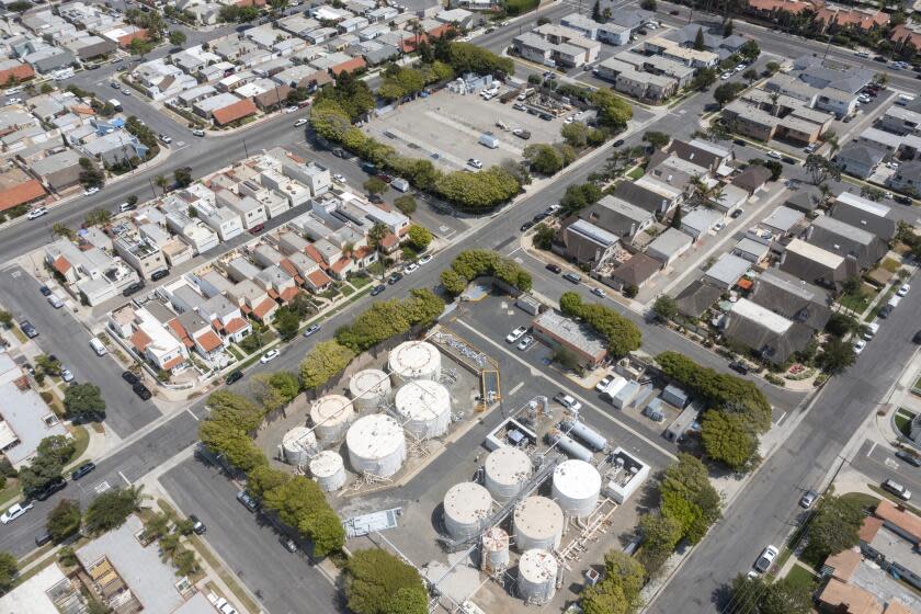 Huntington Beach, CA - July 13: An aerial view of oil wells and storage next to homes in Huntington Beach on Tuesday, July 13, 2021. The California Department of Conservation will soon be releasing a new rule about whether to require health and safety buffer zones around oil wells. (Allen J. Schaben / Los Angeles Times)