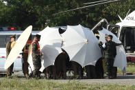 <p>Police and military personnel use umbrellas to cover a stretcher near a helicopter and ambulance at a military airport in Chiang Rai on July 9, 2018, as rescue operations continued for those still trapped inside the cave in Khun Nam Nang Non Forest Park in Thailand. (Photo: Lillian Suwanrumph/AFP/Getty Images) </p>