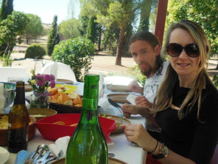 Woman in sunglasses at a table with a man sticking out his tongue.