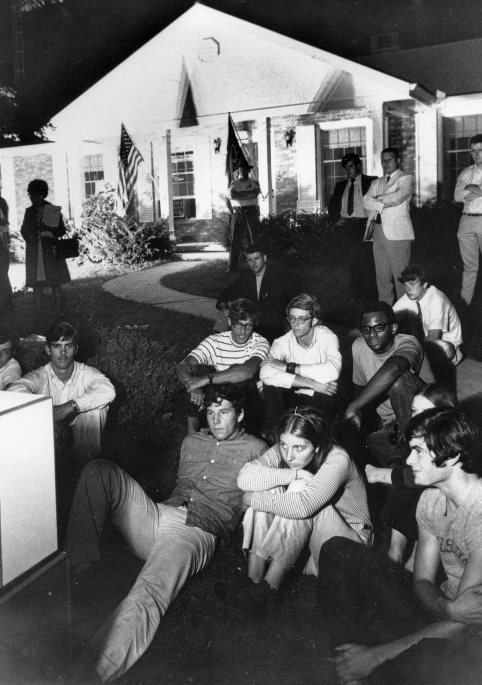 FILE - In this July 20, 1969 file photo, people sit on the lawn of the home of Stephen Armstrong in Wapakoneta, Ohio, to watch astronaut Neil Armstrong walk on the moon. Neil Armstrong helped put Wapakoneta on the map July 20, 1969, when he became the first human to walk on the moon. The late astronaut remains larger than life in the city 60 miles (96.56 kilometers) north of Dayton, where visitors are greeted by the space base-shaped top of the space museum named for him as they exit Interstate 75. (AP Photo/Bill Sauro)