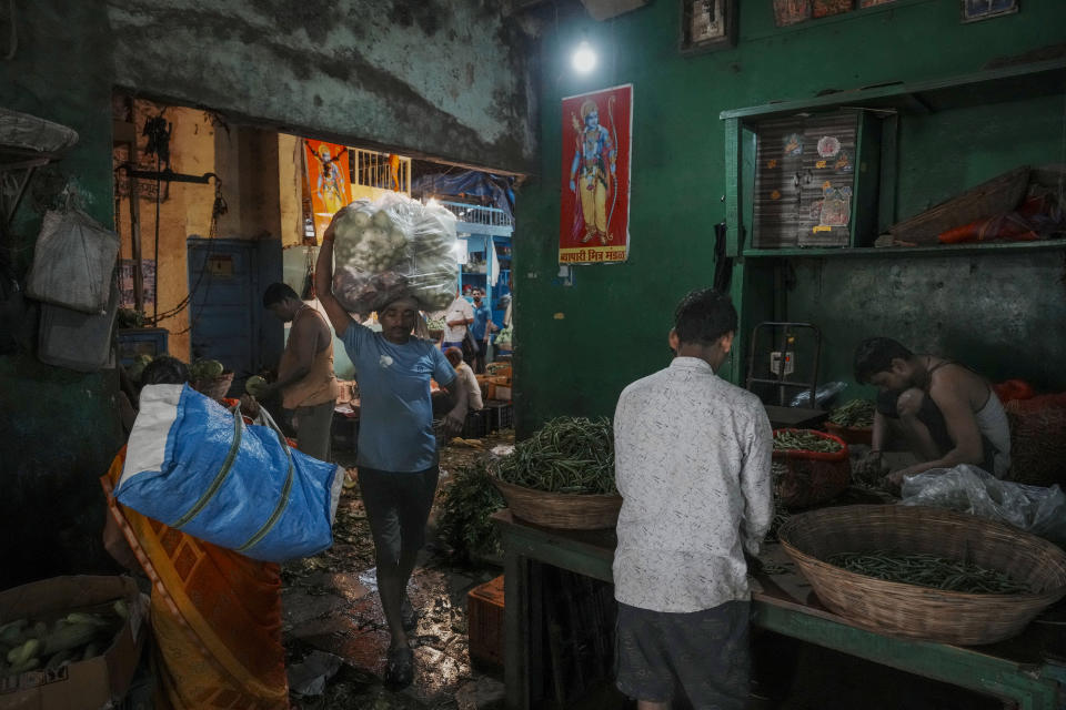 A laborer carries vegetables at a market in Mumbai, India, Tuesday, July 23, 2024. India’s finance minister Nirmala Sitharaman on Tuesday unveiled the first full annual budget of the newly elected government following the national election. (AP Photo/Rafiq Maqbool)