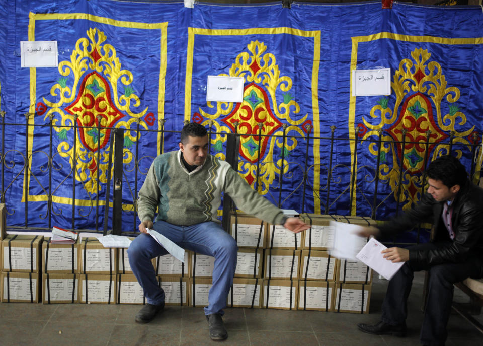 An Egyptian worker sits on boxes of ballots while receiving a list of polling stations from a colleague, at the Giza courthouse, in Cairo, Egypt, Monday, Jan. 13, 2014. The January 14-15 vote on the draft constitution will be the first real test of the post-Morsi regime. A comfortable "yes" vote and a respectable turnout would be seen as bestowing legitimacy, while undermining the Islamists' argument that Morsi remains the nation's elected president. (AP Photo/Amr Nabil)