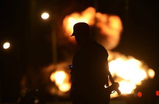 Un soldado ante uno de los tanques en llamas