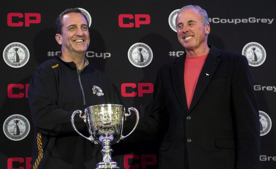 Calgary Stampeders head coach John Hufnagel, right, and Hamilton Tiger-Cats head coach Kent Austin shake hands at a press conference Wednesday Nov. 26, 2014, in Vancouver. The two teams will face each other Sunday in the 102nd CFL Grey Cup. (AP Photo/The Canadian Press, Paul Chiasson)