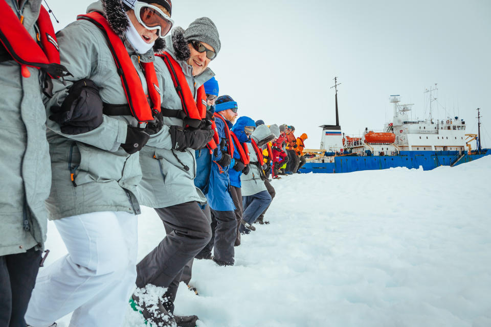 In this Tuesday, Dec. 31, 2013 image provided by Australasian Antarctic Expedition/Footloose Fotography, passengers from the Russian ship MV Akademik Shokalskiy link arms and stamp out a helicopter landing site on the ice near the trapped ship 1,500 nautical miles south of Hobart, Australia. Passengers on board a research ship that has been trapped in Antarctic ice for a week are expected to be rescued by helicopter, after three icebreakers failed to reach the paralyzed vessel, officials said Tuesday. (AP Photo/Australasian Antarctic Expedition/Footloose Fotography, Andrew Peacock) EDITORIAL USE ONLY